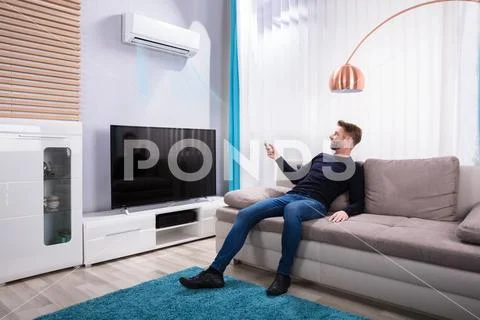 Young Man Using Air Conditioner At Home Stock Photos