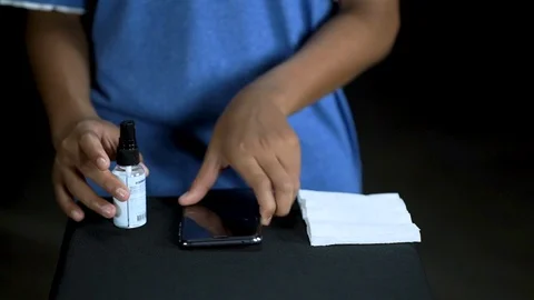 Young man using alcohol rub alternative to washing his phone Stock Footage 126883704