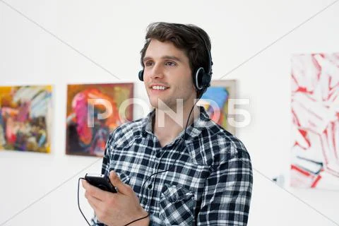 Young Man Using Audio Guide In Art Gallery