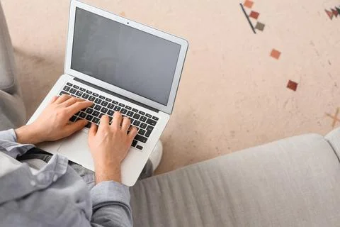 Young man using blank laptop to search online on sofa at home, top view Stock Photos