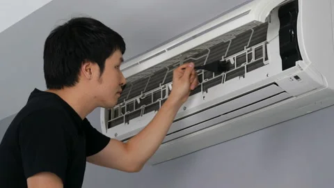 Young man using brush to cleaning the air conditioner indoors at home Video stock 155344724