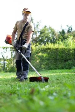 Young Man Using Brush Cutter in Spring Garden Stock Photos