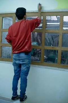 A young man using brush to paint the ceiling Stock Photos