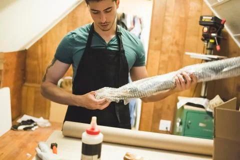 Young man using bubble wrap to prepare parcel for delivery 写真素材