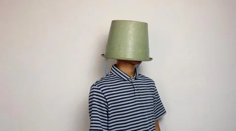 Young man using a bucket on his head on a white background 스톡 사진