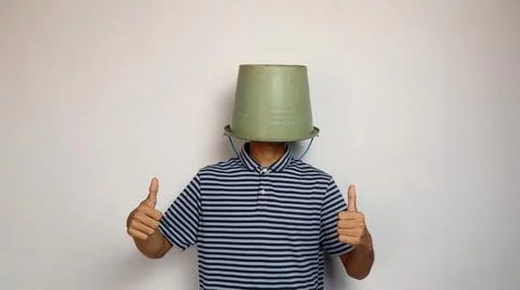 Young man using a bucket on his head on a white background. showing okay ge.. 写真素材