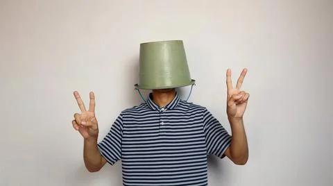 Young man using a bucket on his head on a white background. showing a peace.. Stockfoto's