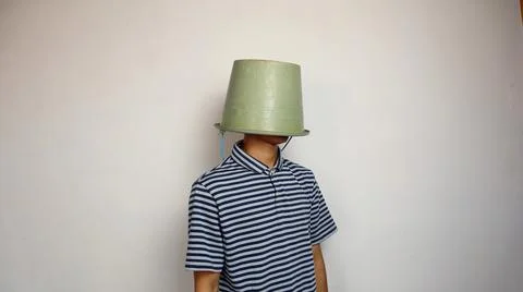 Young man using a bucket on his head on a white background 스톡 사진