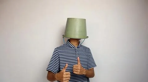 Young man using a bucket on his head on a white background. showing okay ge.. 写真素材