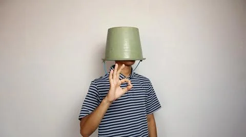 Young man using a bucket on his head on a white background. showing okay ge.. 스톡 사진