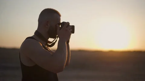 Young man using camera and taking photographs outdoors at sunset Stock Footage 132166291