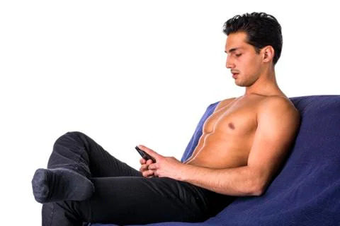 Young man using cell phone sitting on couch Stock Photos