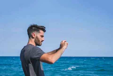 Young man using cell phone to take photo at beach Stock Photos