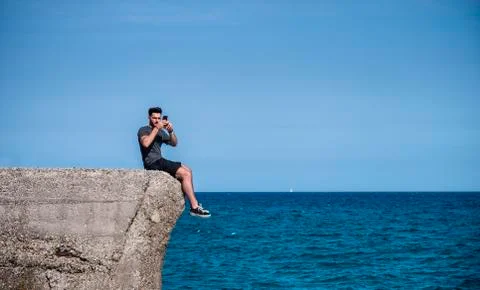 Young man using cell phone to take photo at beach Stock Photos