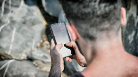 Young man using cell phone to send text message Stock Photos