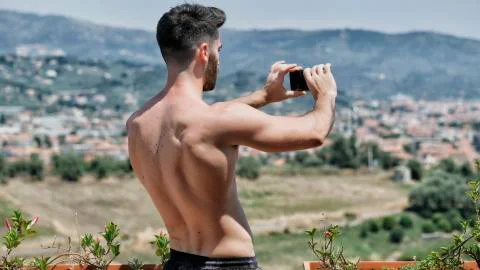 Young man using cell phone to film landscape Stock Photos