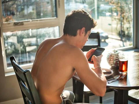 Young man using cell phone during breakfast Stock Photos