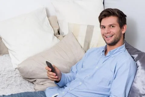 Young man using cellphone on couch Stock-Fotos