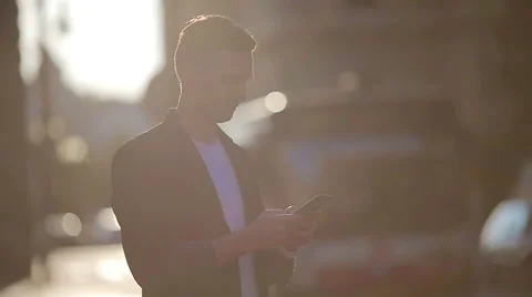 Young man using cellphone outdoors on the street in soft light Stock Footage