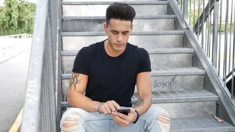 Young man using cellphone outdoors in urban setting Stock Photos