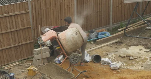 Young man using a cement mixer on building site mid-shot Stock Footage 246381802