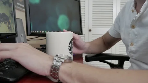 A young man using a computer and drinking coffee 스톡 동영상 75486985