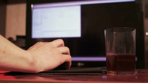 Young man using a computer mouse, sitting at home, drinking beer Stock Footage 74993797
