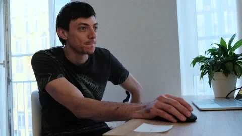 Young man using computer mouse something tells, looking to the side Vídeo Stock 135743506