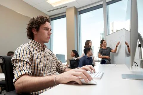 Young man using computer in office looking, co-workers having discussion in 写真素材
