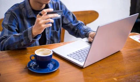 Young Man Using Credit Card for Online Shopping on Laptop in Cafe Stock Photos