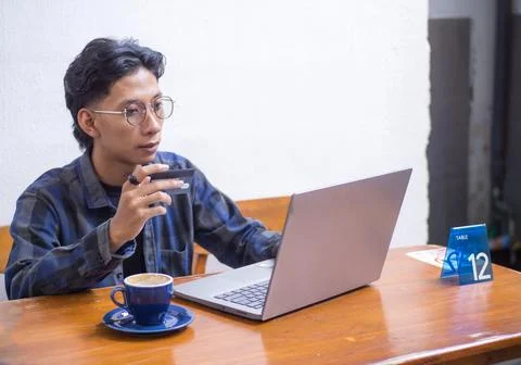 Young Man Using Credit Card for Online Shopping on Laptop in Cafe Stock Photos