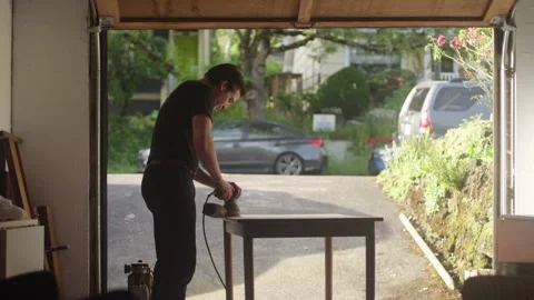Young man using a detailing sander while restoring a wooden table Video stock 134287963