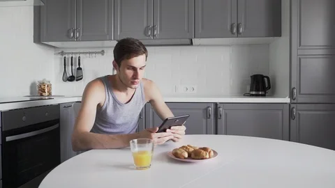 Young man using digital tablet for read news while sitting in kitchen at home Stock Footage 127481814