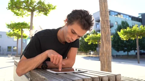 Young man using digital tablet and enjoying music while lying on bench at Stock Footage 136981765