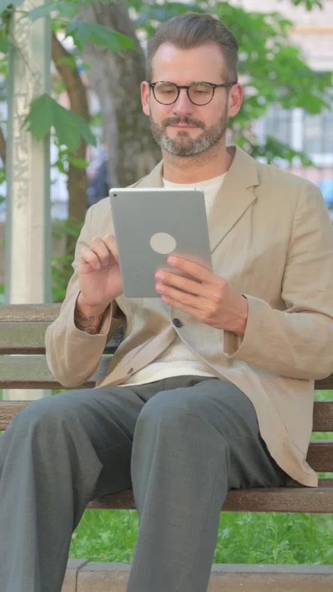 Young Man Using Digital Tablet while Sitting Outdoor, Vertical Video Video stock 319047551
