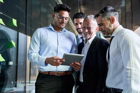 Young man using a digital tablet showing his project to his boss and colleagues Stock Photos