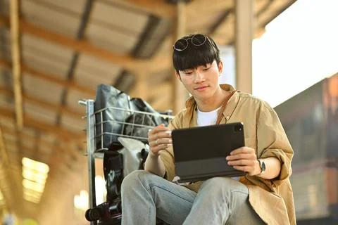 Young man using digital tablet, checking the route of trip on map while waiting Stock Photos