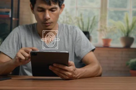 Young Man Using Digital Tablet with Fingerprint Scanner Technology at Home Stock Photos
