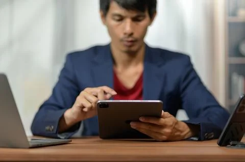 Young Man Using Digital Tablet for Work or Study in Modern Office Setting Stock Photos