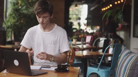 Young man using earphones with wires to listing the music in cafe, modern 스톡 동영상 112594542