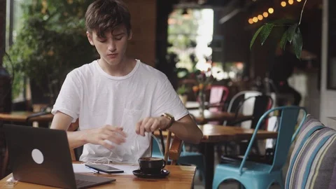 Young man using earphones with wires to listing the music in cafe, modern 動画素材 112594564