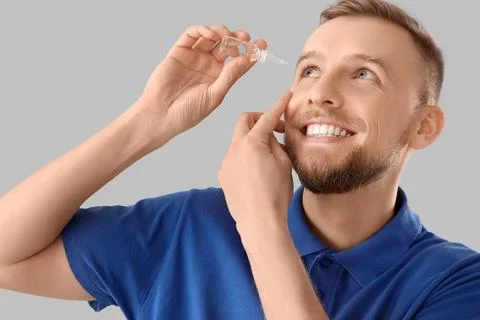 Young man using eye drops on light background, closeup Stock Photos