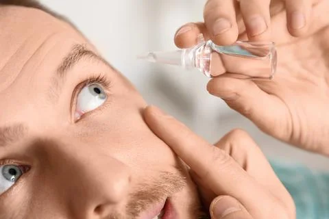 Young man using eye drops at home, closeup Stock Photos