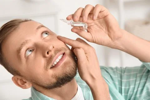 Young man using eye drops at home, closeup Stock Photos
