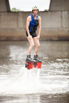 Young man using flyboard machine on river Stock Photos