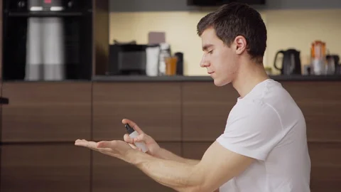 Young man using hand sanitizer while working on laptop Stock Footage 128762417