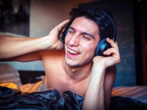Young Man Using Headphones Lying Alone On His Bed Stock Photos