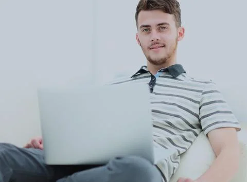 Young man using his laptop in bright living room. Stock Photos