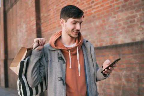 Young man using his mobile phone on the street. Stock Photos