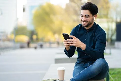 Young man using his mobile phone outdoors. Stock Photos